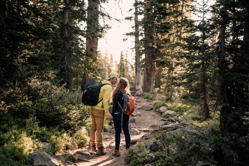 a man and woman walking down a trail in the woods