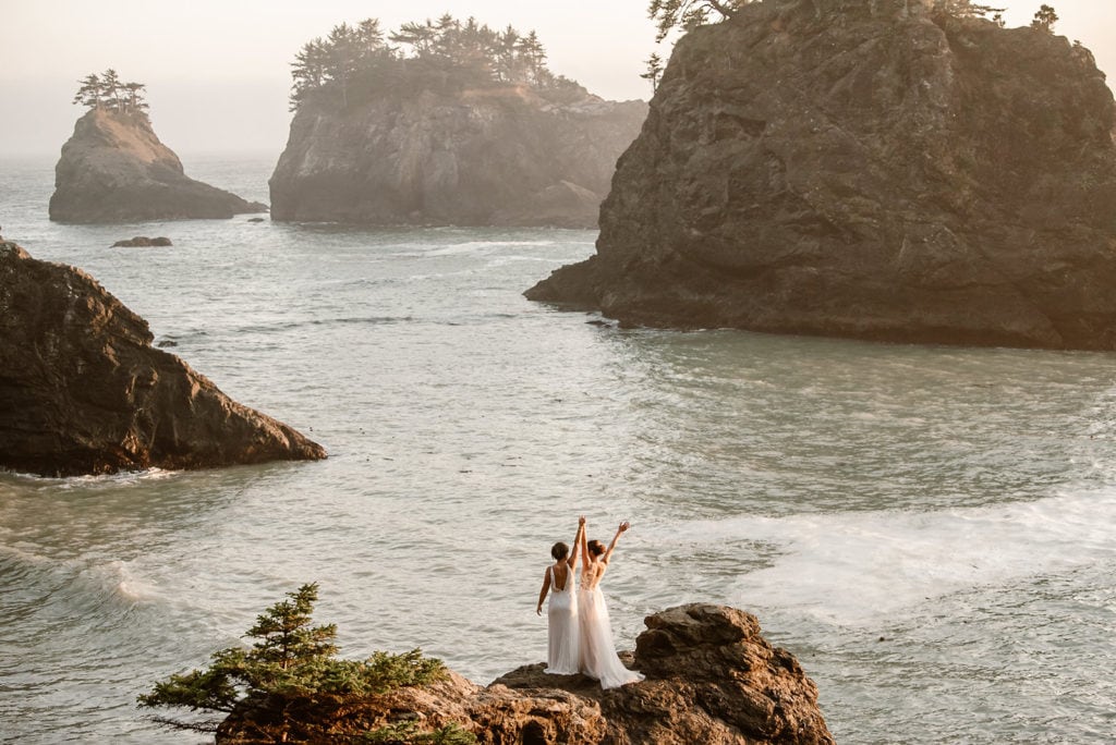 two people standing on rocks near the ocean