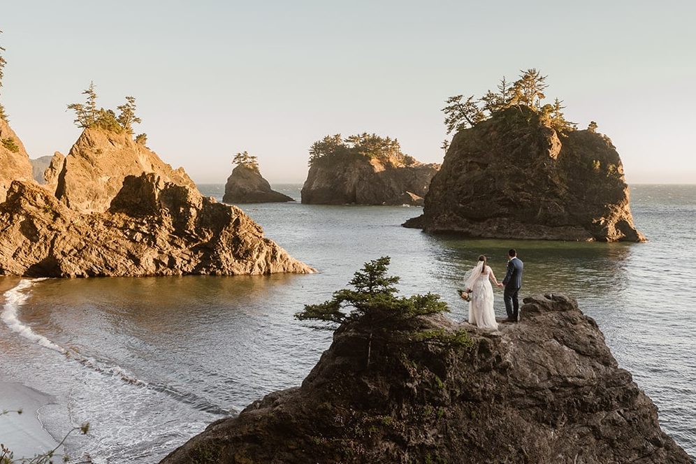 a bride and groom standing on the edge of a cliff