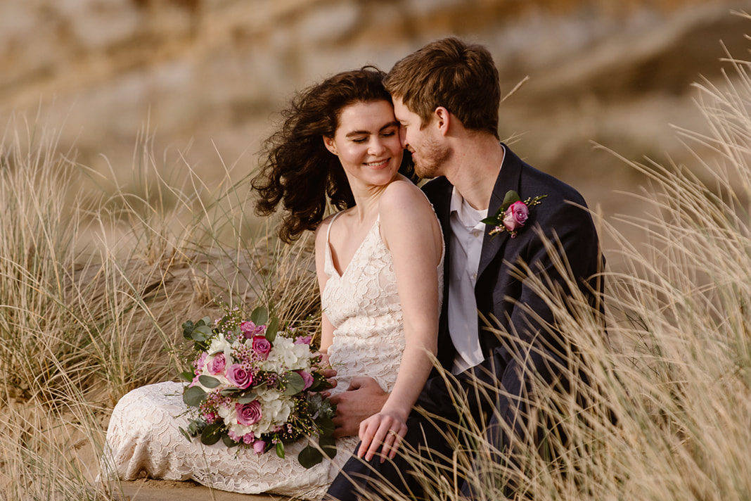 a bride and groom are sitting in the sand