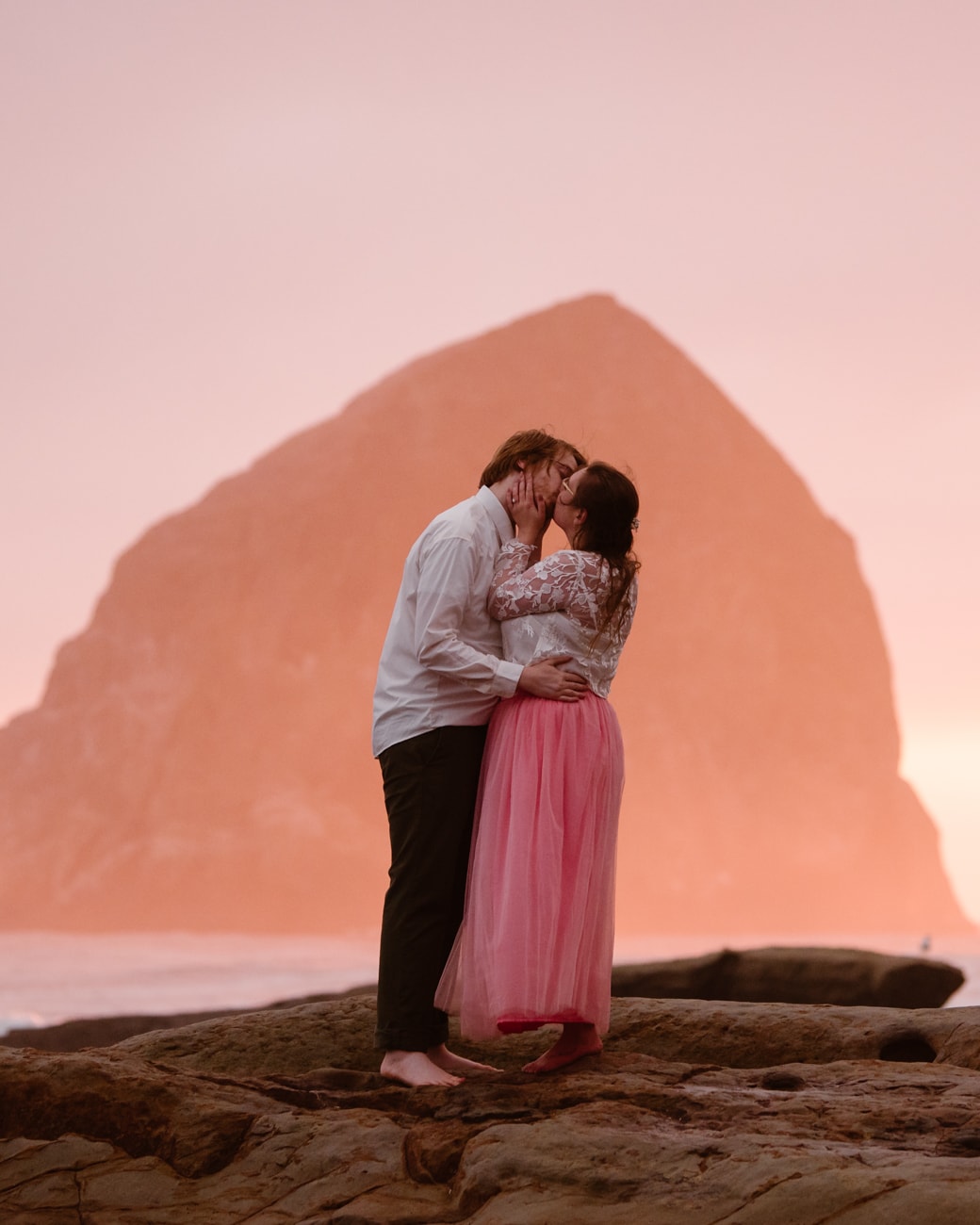 a man and woman kissing on the beach