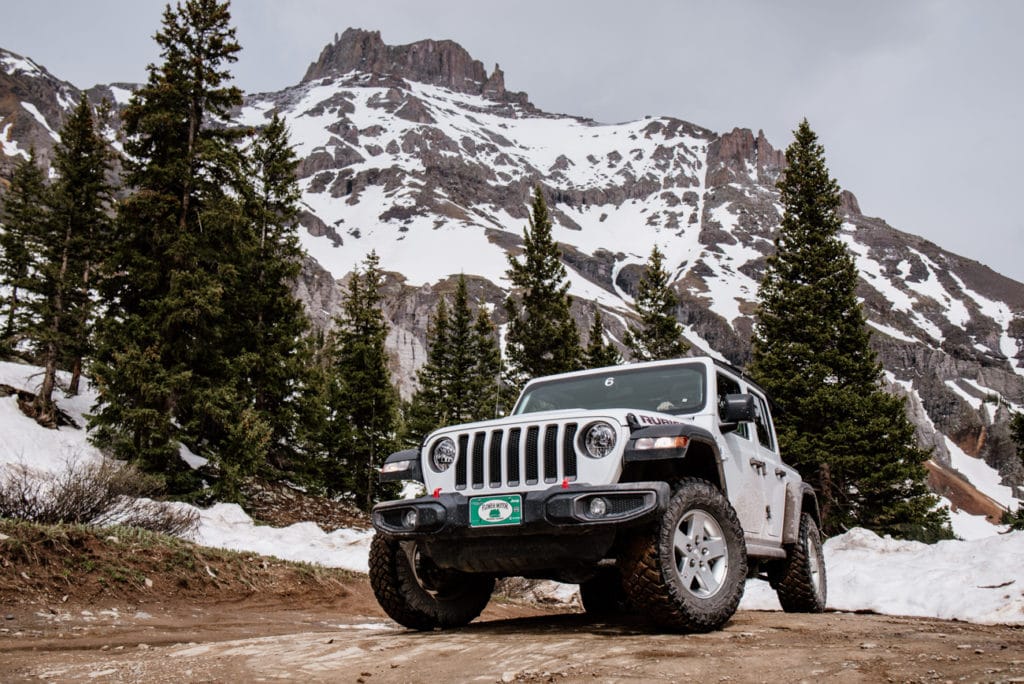 a white jeep parked in front of a mountain