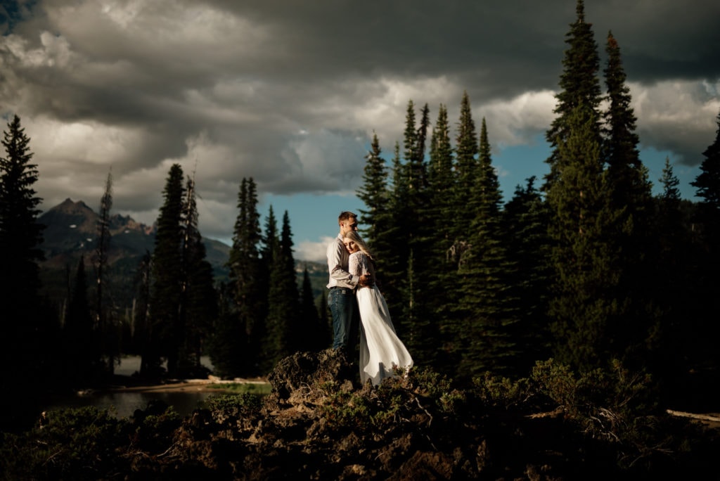 a bride and groom standing on top of a mountain