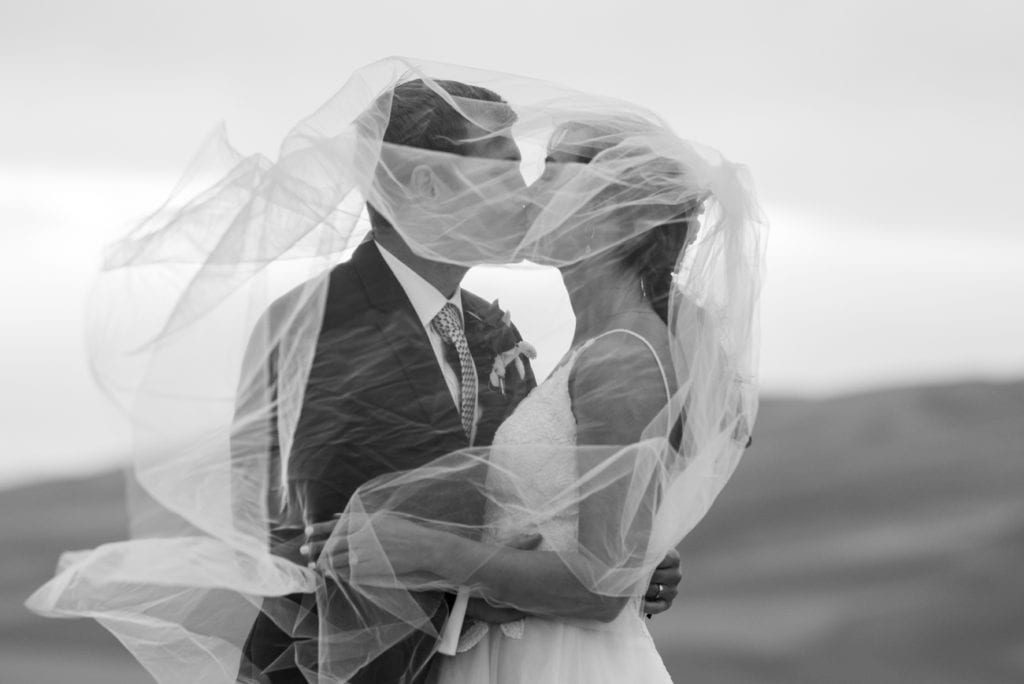 a bride and groom kissing under a veil