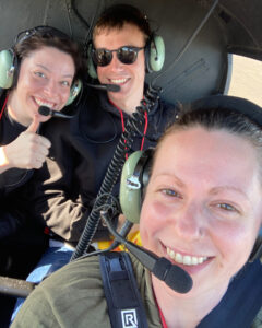 three people sitting in a small plane with headsets on