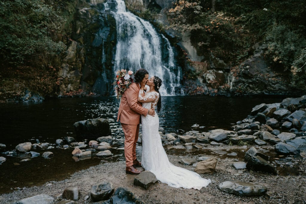 a bride and groom standing in front of a waterfall in Oregon