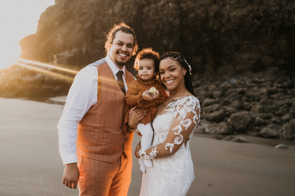 a man and woman holding a baby on the beach