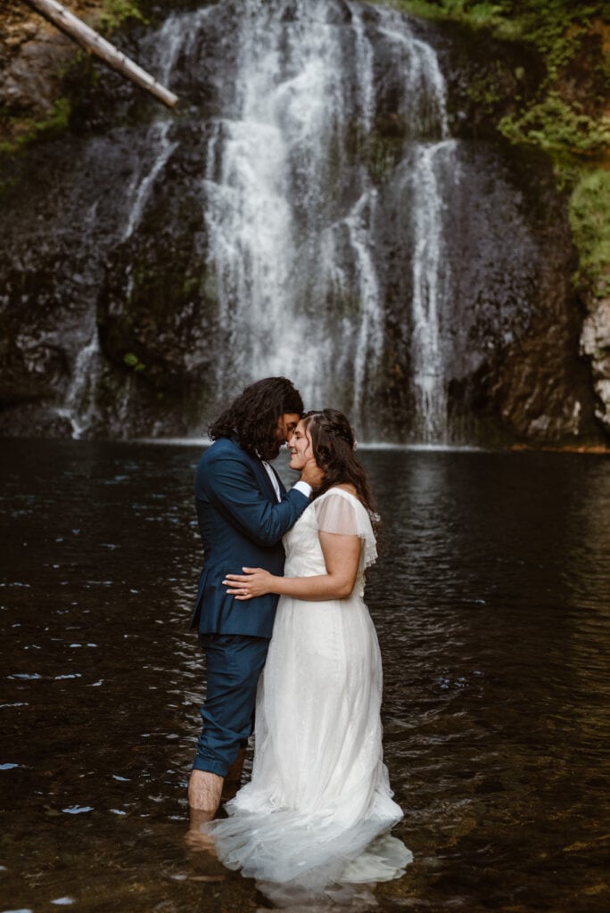 a bride and groom standing in front of a waterfall in Oregon