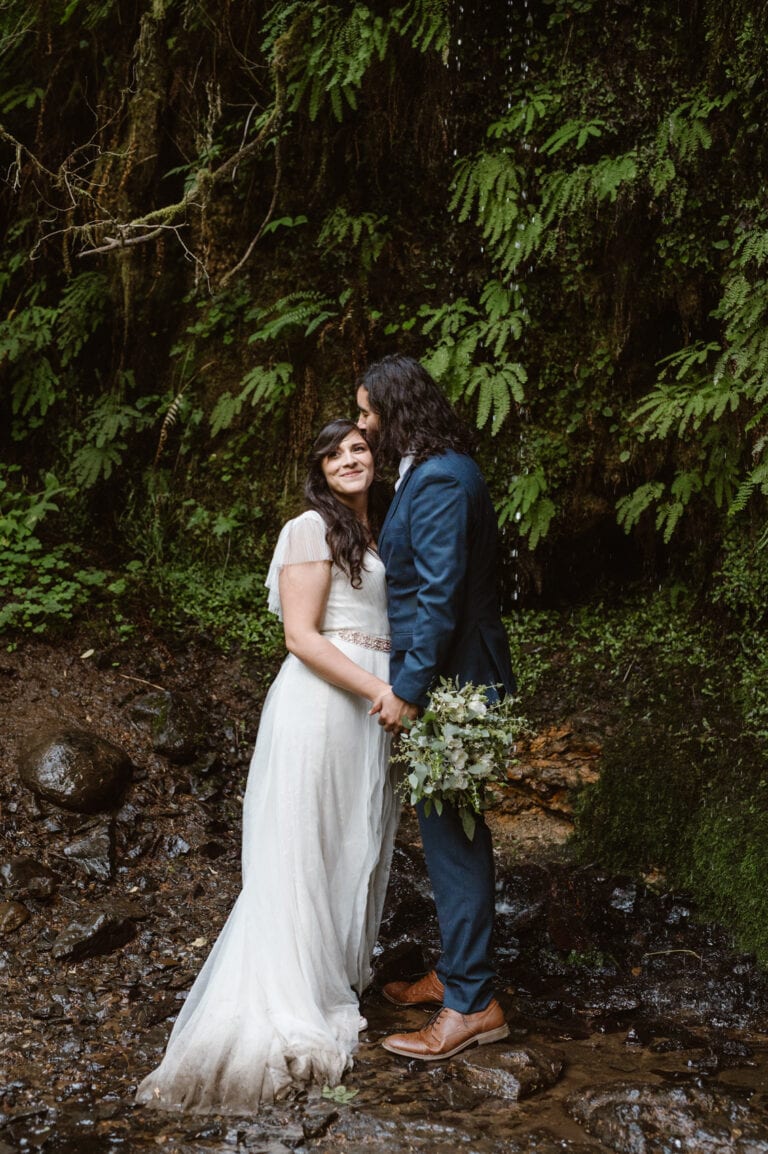 a bride and groom standing in front of some trees