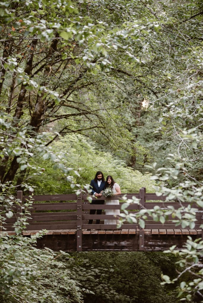 two people sitting on a bench in the woods