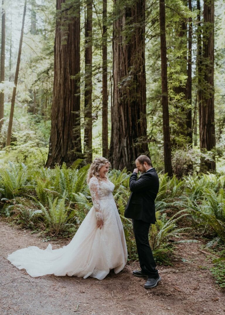 a bride and groom standing in the woods