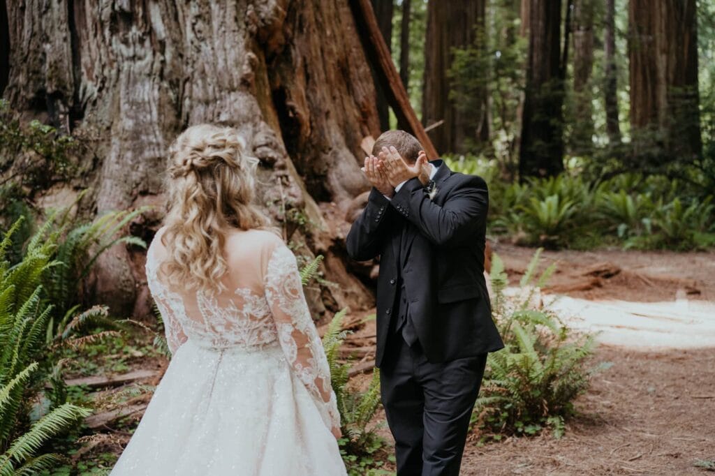 a bride and groom walking through the woods