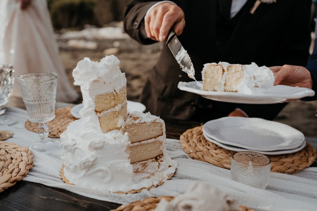 a person cutting a piece of cake on top of a table