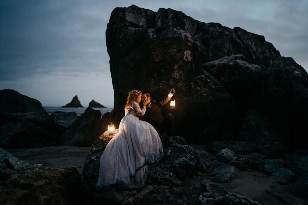 a bride and groom sitting on rocks with their lights in the dark