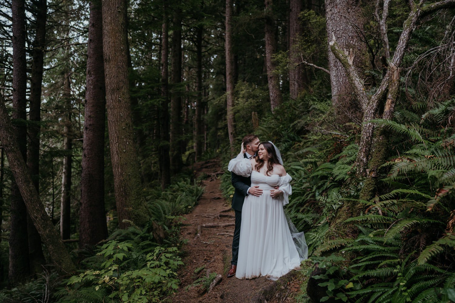 a bride and groom kissing in the woods