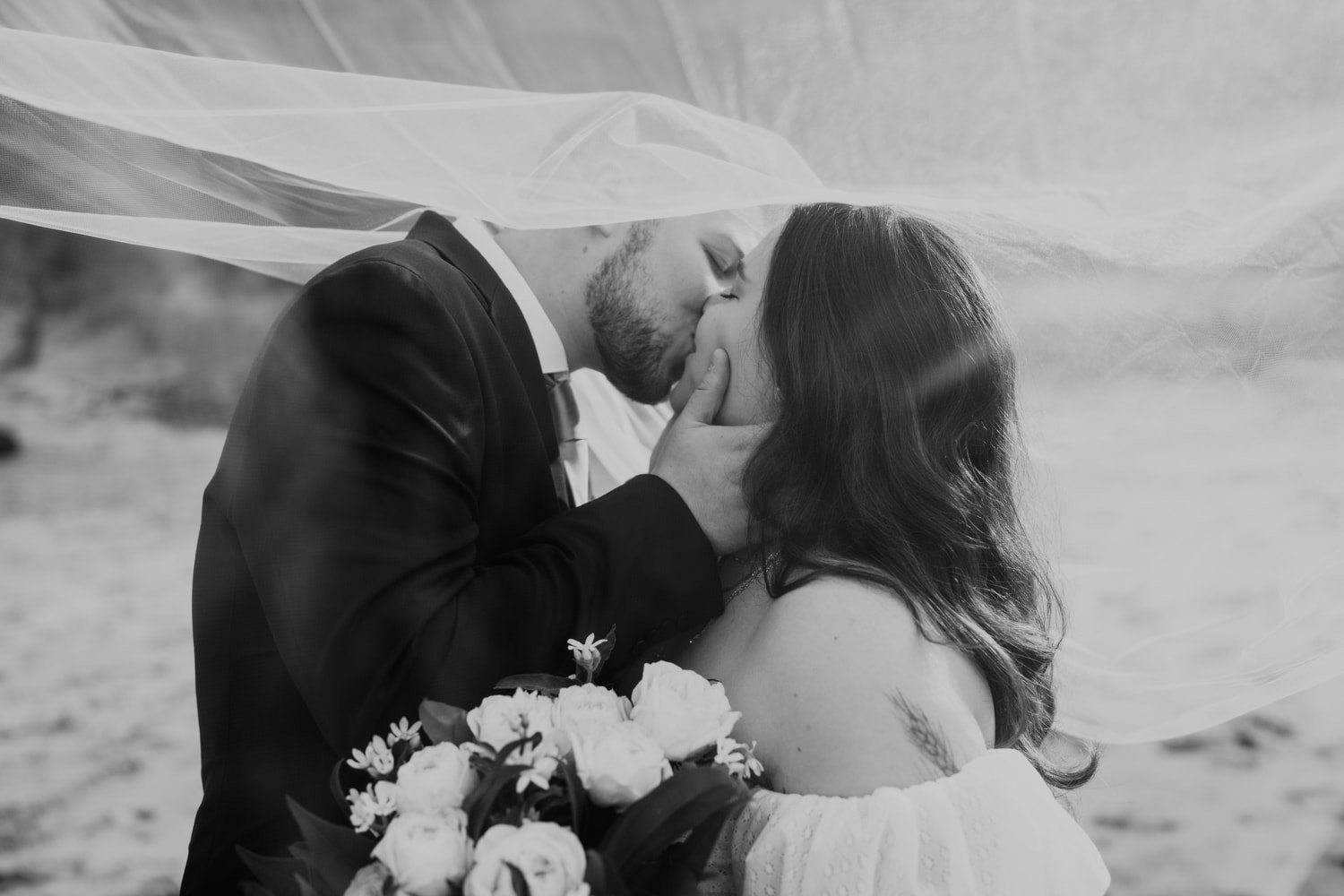 A black and white photo of the bride and groom sharing a kiss after their wedding ceremony at Hug Point.
