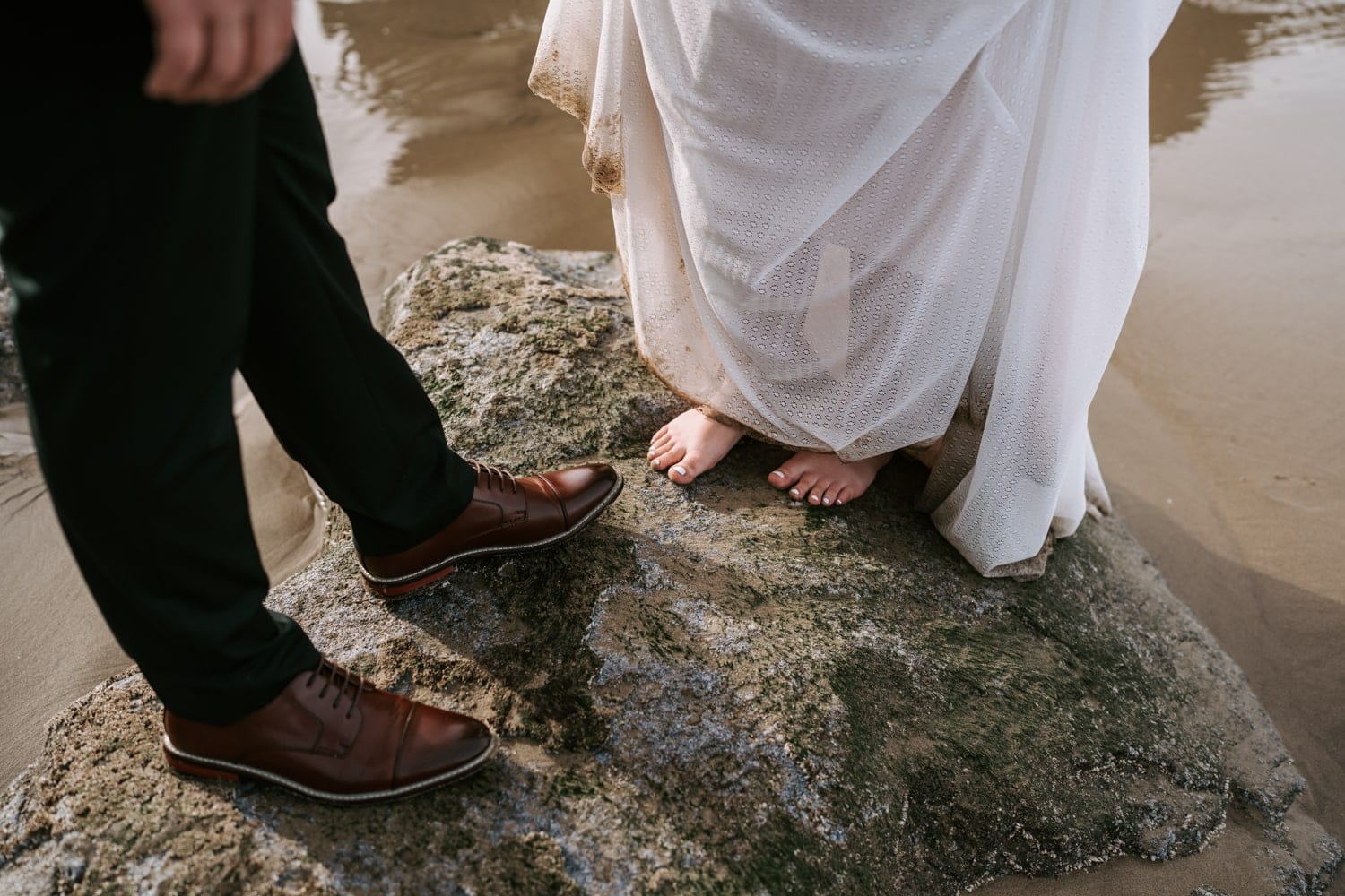 The bride and groom stand in the wet sand during their elopement at Hug Point.