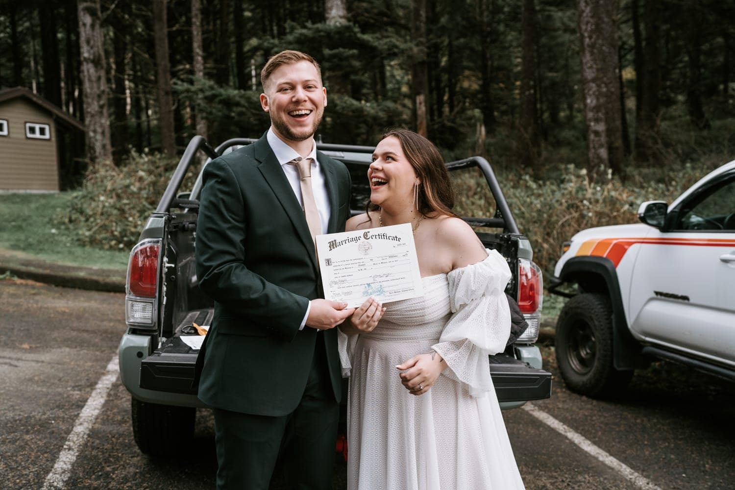The wedding couple pose with their marriage license after getting married at Hug Point on the Oregon Coast.